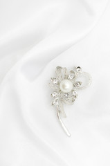 Silver brooch with pearls and diamonds on silk fabric