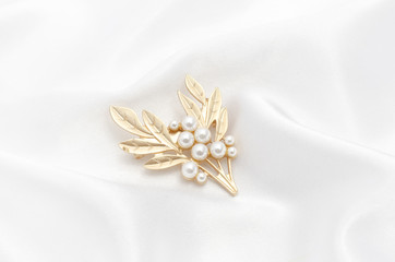 Golden brooch twig with pearls on silk fabric
