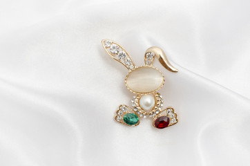 Golden brooch bunny with diamonds and moonstone on silk fabric