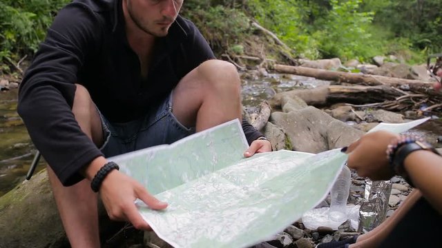 Hikers with a map in a camping near the creek
