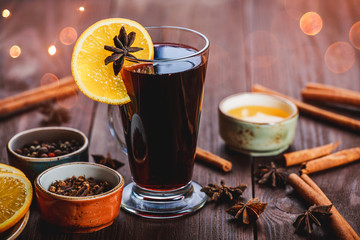 Christmas mulled wine with cinnamon, anise stars, honey and orange slices on wooden background with Holiday light
