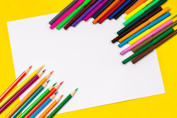 School supplies and white sheet on a bright yellow background, ready for your design