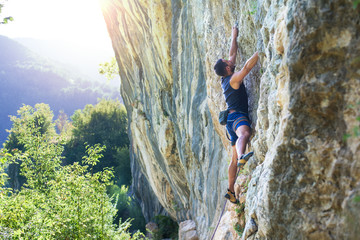 Rock climber with hand in chalk bag hanging on boulder