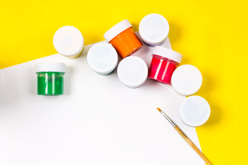 School supplies and white sheet on a bright yellow background, ready for your design
