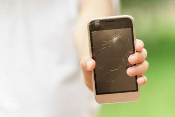 little girl in desperation is holding a phone with a broken screen