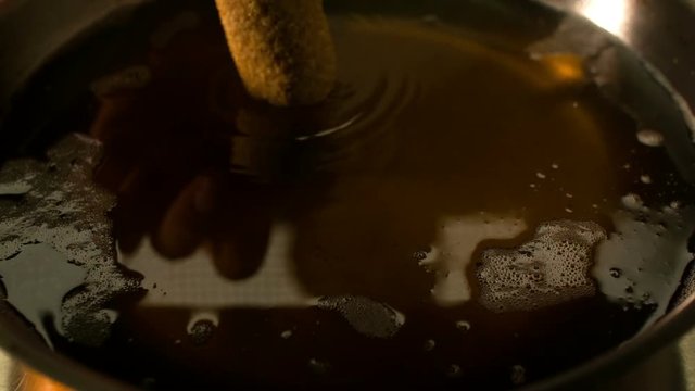 kibbeh pieces falling into frying oil. super slow