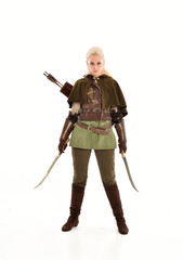 full length portrait of a blonde girl wearing green and brown medieval costume, holding a bow and arrow. isolated on white background.