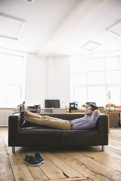 Tired businessman relaxing on sofa in light office room