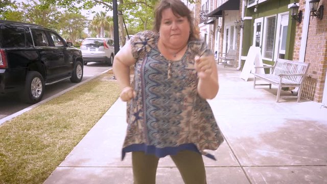 A crazy plus sized woman dancing in the streets celebrating achievement