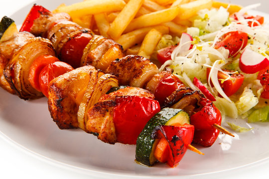 Kebabs - grilled meat and vegetables on white background