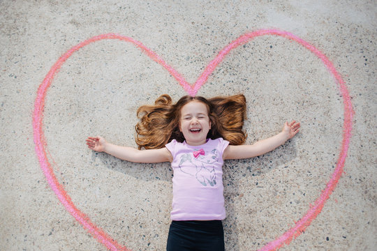 Cute young girl laughing while laying inside of a heart