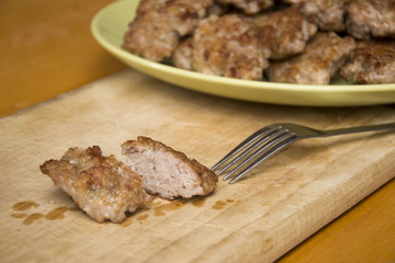 Mini pork patties, meatballs with bread, tomato sauce and fork on wood