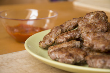 Mini pork patties, meatballs with bread, tomato sauce and fork on wood