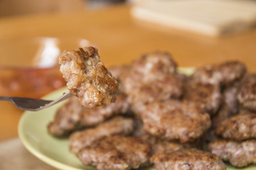 Mini pork patties, meatballs with bread, tomato sauce and fork on wood