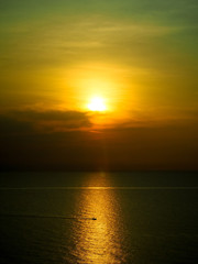 Silhouette photo of fisherman rowing a fishing boat in the middle of the sea. The light of the sunset in the evening reflects the beautiful golden sea.