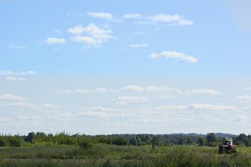 Obraz premium Landscape of a green field against a blue sky With an old tractor