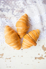 Beautiful and delicious croissants on the background of old laces and white table.