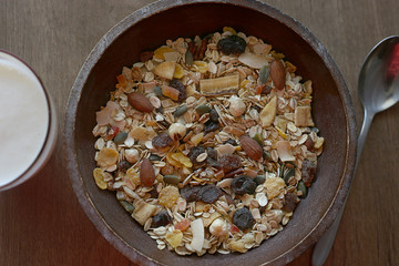 Muesli with nuts and tropical dried fruits. Healthy breakfast: flakes cereal in wooden plate top view.