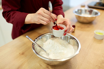 chef hands adding food color into bowl with flour