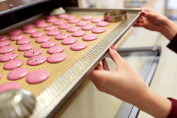 chef with macarons on oven tray at confectionery