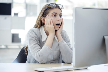 Shocked young woman looking at computer