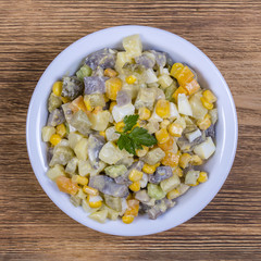 Salad of potato, mushrooms, cucumber, onion, carrot and corn in plate. Close up