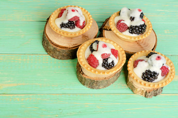 Tartlets with berries and cream, on decorative stumps.