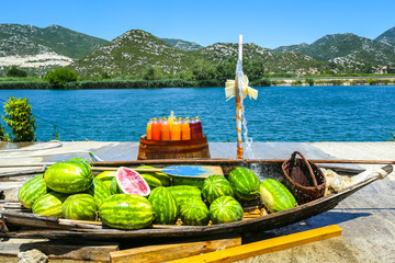 Watermelons in a boat and fresh homemade fruit juices on a barrel displayed at a food stand next to the river Neretva in Croatia.