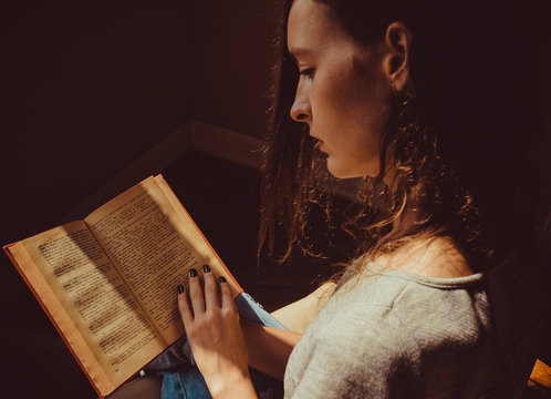 Spending free time by reading books. Girl preoccupied with reading old interesting paper book. Natural light. Enjoy morning. Warm atmosphere. Knowledge, learning and education concept. Woman bookwarm.