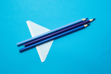 Naklejka premium Blue rocket from school pencils and paper on a blue background.
