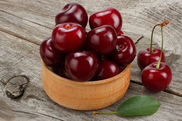 cherries in bowl on old wooden background