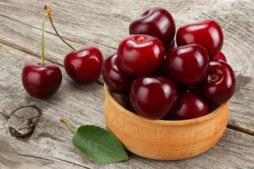 cherries in bowl on old wooden background