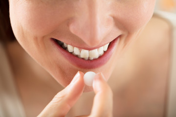 Close-up Of Female Taking White Pill