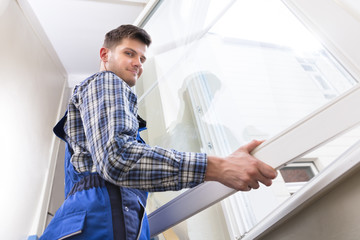 Naklejka na ściany i meble Male Repairman Installing Window
