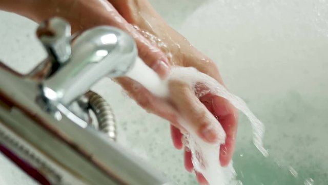 girl washes her hands in a round bath with foam and red rose petals