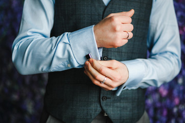Close up image of a fashion the hands of a young businessman, handsome model man in casual cloth costume. Wearing the vest in the cage, black jeans and blue shirt.