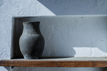 Old jug stands on a rustic window of the house