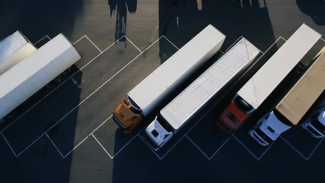 Moving Aerial Top View of Parked Semi Trucks with Cargo/ Refrigerator Trailers Standing on their Dedicated Parking Places. Shot on RED EPIC-W 8K Helium Cinema Camera.