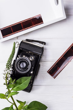 Old vintage camera, film and flower on wooden background. Black and white illustration