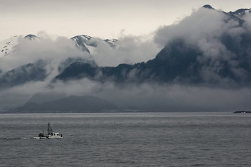 Alaskan fishing trawler along a foggy coastline