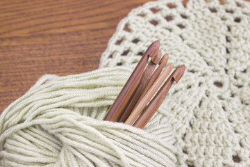 Wooden natural bamboo crochet hooks, doily and yarn ball on the table. Creative work place for homemade crafts. Top view. - obrazy, fototapety, plakaty