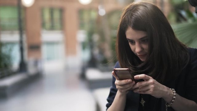 Close up of a pretty young girl with dark hair using a smartphone in Botanical Garden Inside Atocha Train Station, Madrid. Handheld real time close up shot