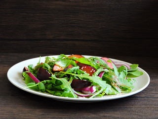 Fitness salad with arugula and plums on a plate. Nourishing fitness slimming salad.