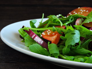 Fitness salad with arugula and plums on a plate. Salad for proper nutrition.