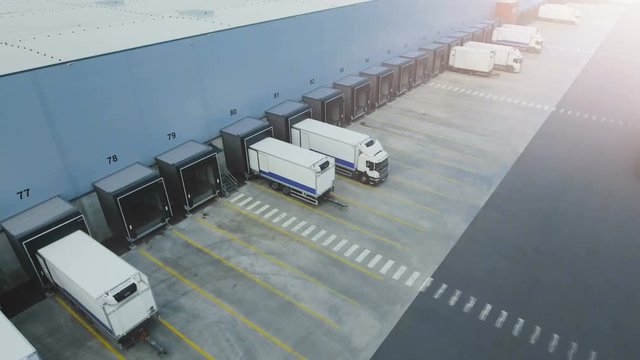 Moving Aerial Side Shot of Industrial Warehouse Loading Dock where Many Truck with Semi Trailers Load/ Unload Merchandise.  Shot on RED EPIC-W 8K Helium Cinema Camera.