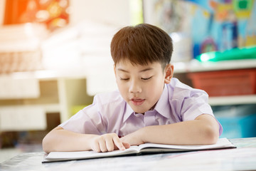 Happy asian child reading book with smile face at school