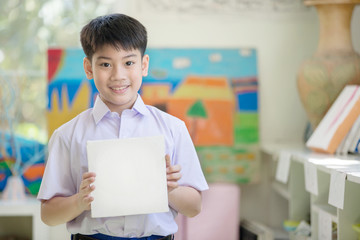 Happy asian boy hand holding blank paper board and looking at camera