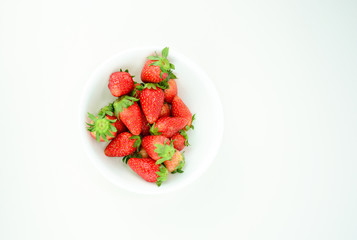Fresh strawberries with leaf in a white bowl on white background