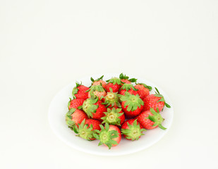 Fresh strawberries with leaf in a white plate on white background
