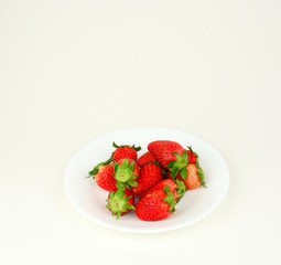 Fresh strawberries with leaf in a white plate on white background